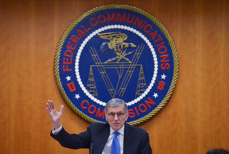 Tom Wheeler speaks in front of the FCC logo from a podium, in 2015.