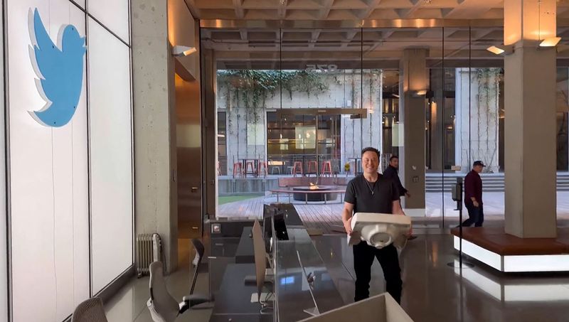 Elon Musk pictured holding a sink inside an industrial-chic office with concrete pillars and floor-to-ceiling windows. 