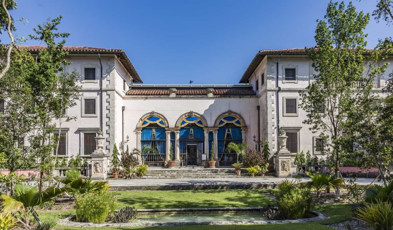 The Vizcaya Estate with a terracotta roof and large arched doorways under blue sky in Miami, Florida.